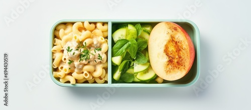 Macaroni salad with chicken and apples arranged in a school lunch bento box in a flat lay.