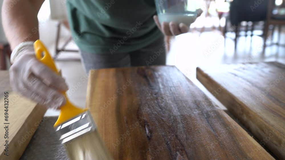 Worker applying oil with a brush, wood renovation