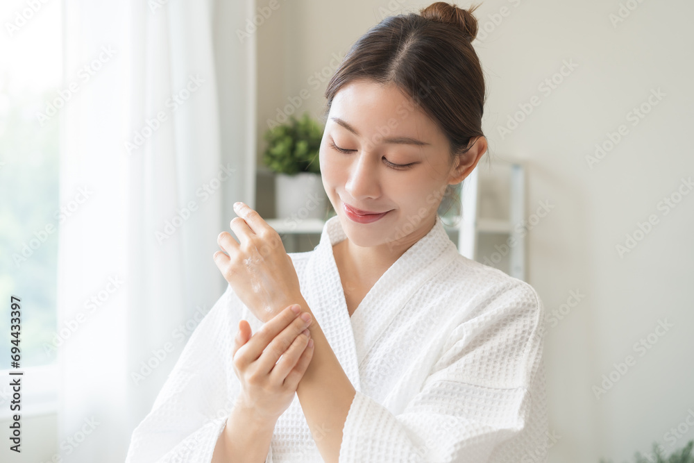 Health care, beauty smile pretty asian young woman in bathrobe, towel after shower bath at home, finger applying moisturizer on her back hand. Skin body cream moisturizing lotion, routine in morning. Health care, beauty smile pretty asian young woman in bathrobe, towel after shower bath at home, finger applying moisturizer on her back hand. Skin body cream moisturizing lotion, routine in morning.