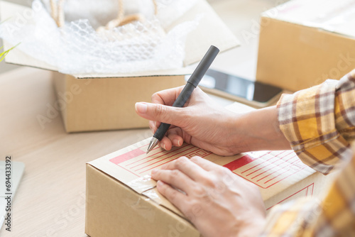 Online seller store, owner small business entrepreneur asian young woman packing product in box, writing address for sending and check purchase order, prepare parcel sent delivery company to customer.