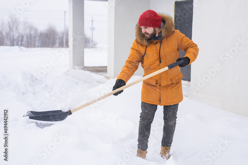 Man cleaning snow from sidewalk and using snow shovel. Winter season