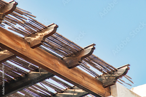 Vigas de madera de un alero en una casa de playa. Primer plano del detalle de la construcción con cañas. Las Negras, Almería, España. photo