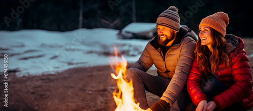 Couple enjoying a romantic campfire in winter outdoors. 