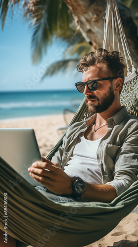 Freelancer in a hammock working by the sea. young businessman working by the sea. The concept of remote work photo