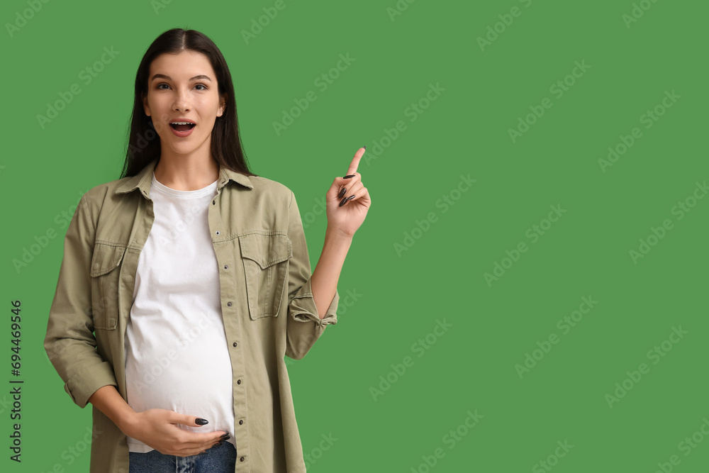 Surprised pregnant woman pointing at something on green background Surprised pregnant woman pointing at something on green background