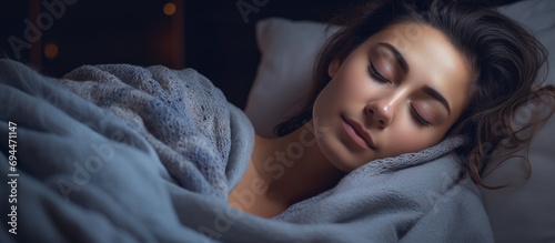 Beautiful young woman peacefully sleeping in bed, covered with a blanket. photo