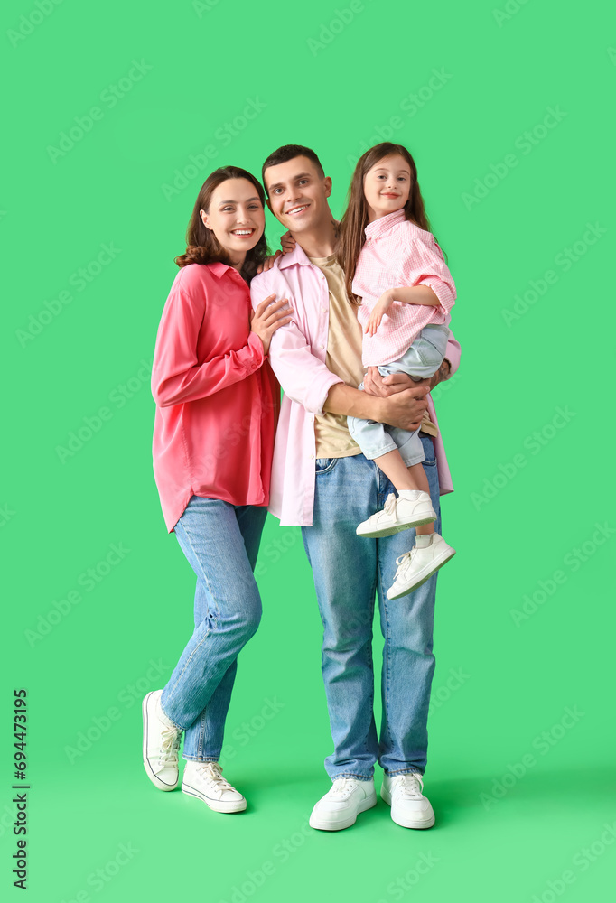 Fototapeta premium Little girl with her parents on green background