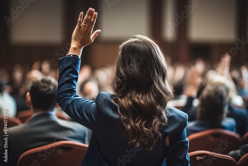 a businesswoman in a conference looking at an audience raising her hand