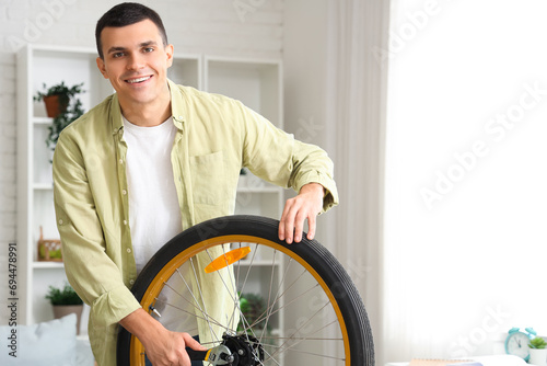 Young man repairing bicycle wheel with wrench at home