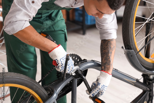 Young mechanic repairing bicycle in workshop, closeup
