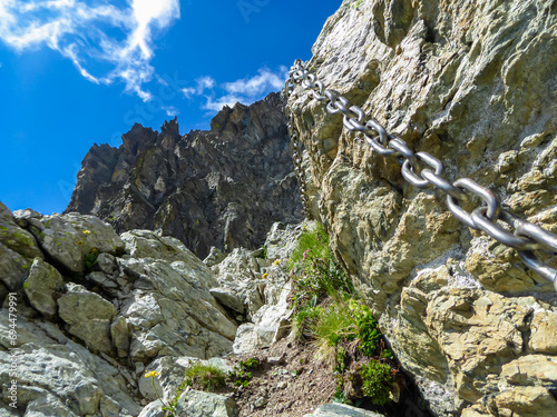 Via ferrata along steep and rocky walls leading to mountain summit Monte Viso (Monviso) in Cottian Alps, Cuneo, Piemonte, Italy, Europe. Hiking trail with iron chains for safety. Wanderlust, climbing photo