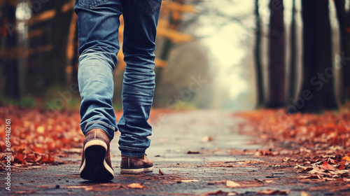 Person Walking Amidst Fallen Leaves in Jeans and Boots photo