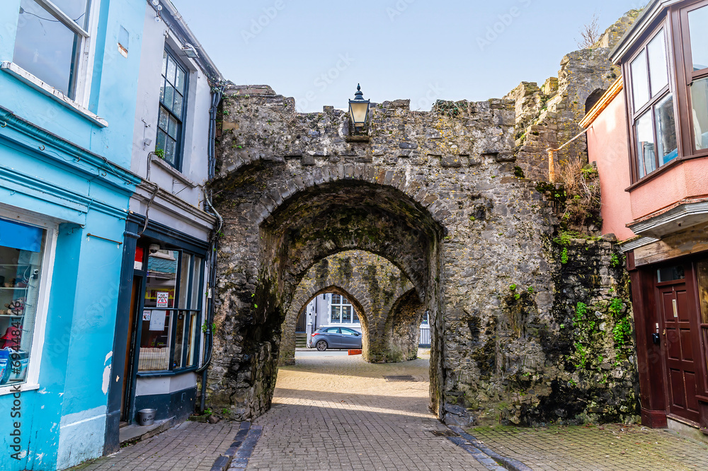 A view from Saint Georges Street towards the five arches entrance in the town walls in Tenby, Wales on a sunny day