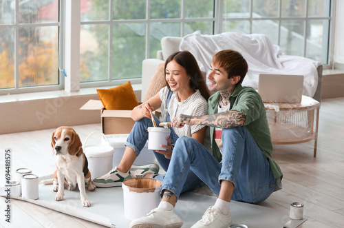 Young couple with paint can and Beagle dog during repair in their new house