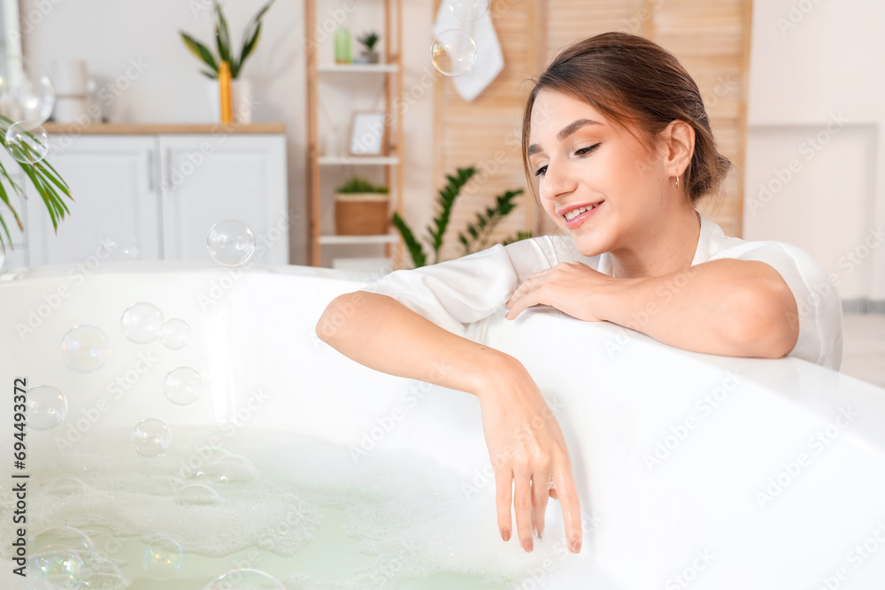 Beautiful woman with soap bubbles near bathtub at home Beautiful woman with soap bubbles near bathtub at home