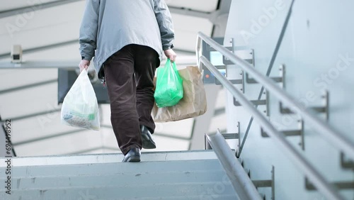 Person carries grocery bags during daily commute walking up the stairs heading toward train platform photo