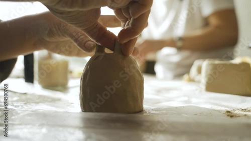 A woman makes a ceramic pot and attaches the legs. Close-up. Creative hobby. photo