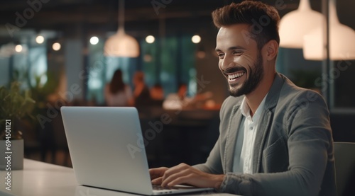 cheerful man smiles in office and looking at laptop