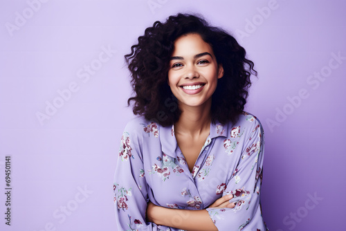 Jeune femme brune souriante avec un chemisier fleuri sur fond violet photo