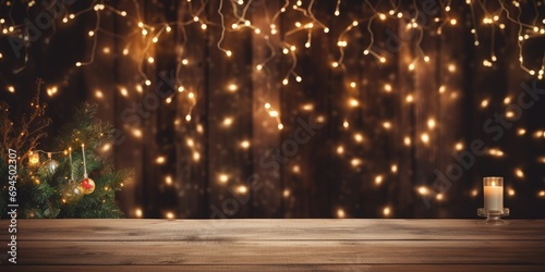 A wooden table with fairy lights below and a festive Christmas backdrop of tree and lights. © Lasvu
