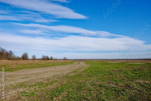 A dirt road stretching into the distance under a blue sky.