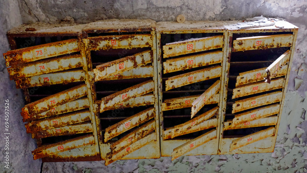 Old, rusted mailboxes with numbers painted in red.