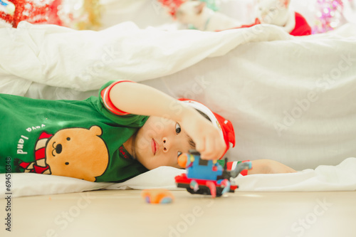 Asian boy playing with train toy in room decorated for Christmas