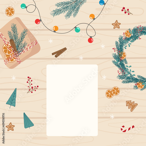 Christmas preparing flat lay square background. Christmas decorations, garland and white blank empty sheet for writing a list, wishes, card, letter on light wooden table. Template for holiday design