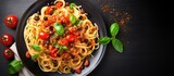 Italian pasta dish with tomatoes, olives, capers, anchovies, and basil, viewed from the top.