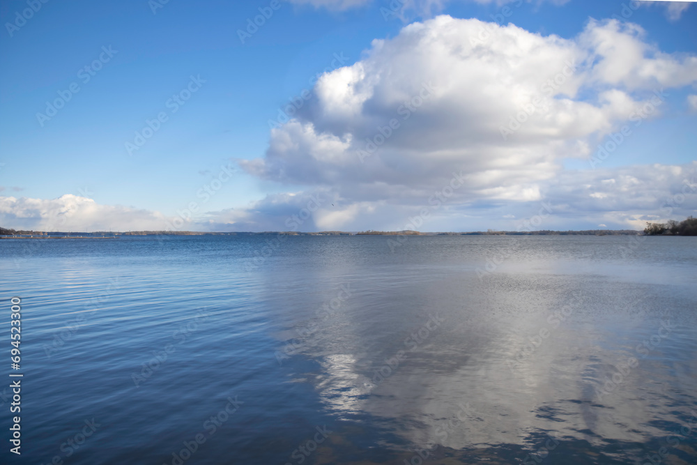 Large white cloud reflected in a lake, blue sky, daytime, nobody