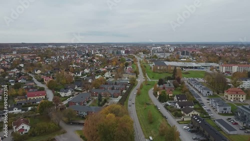Footage following a road with cars driving towards a roundabout on a cold autumn day from above