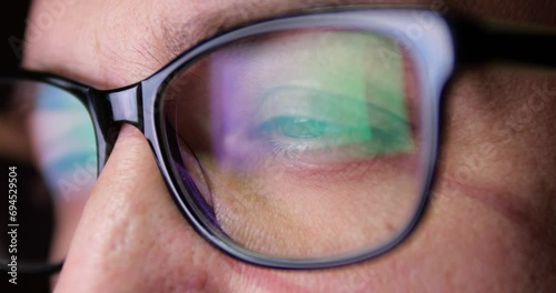 Close-up of eyes in glasses of businessman programmer. Work behind a monitor or laptop to create artificial intelligence. finance on the Internet. Hacker and network security. photo