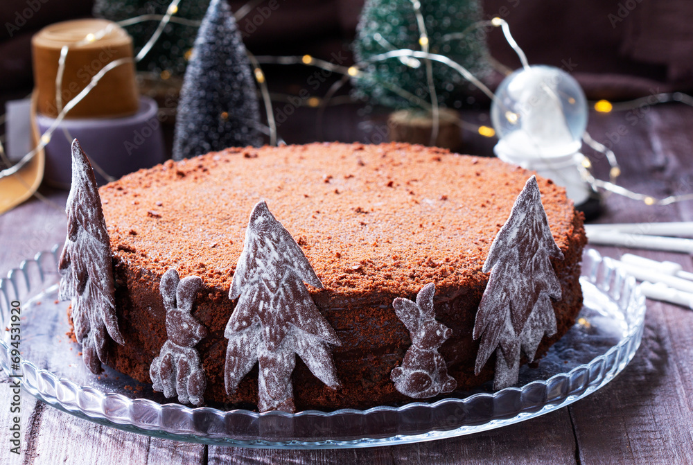 Chocolate honey cake in a Christmas decoration on a wooden background.