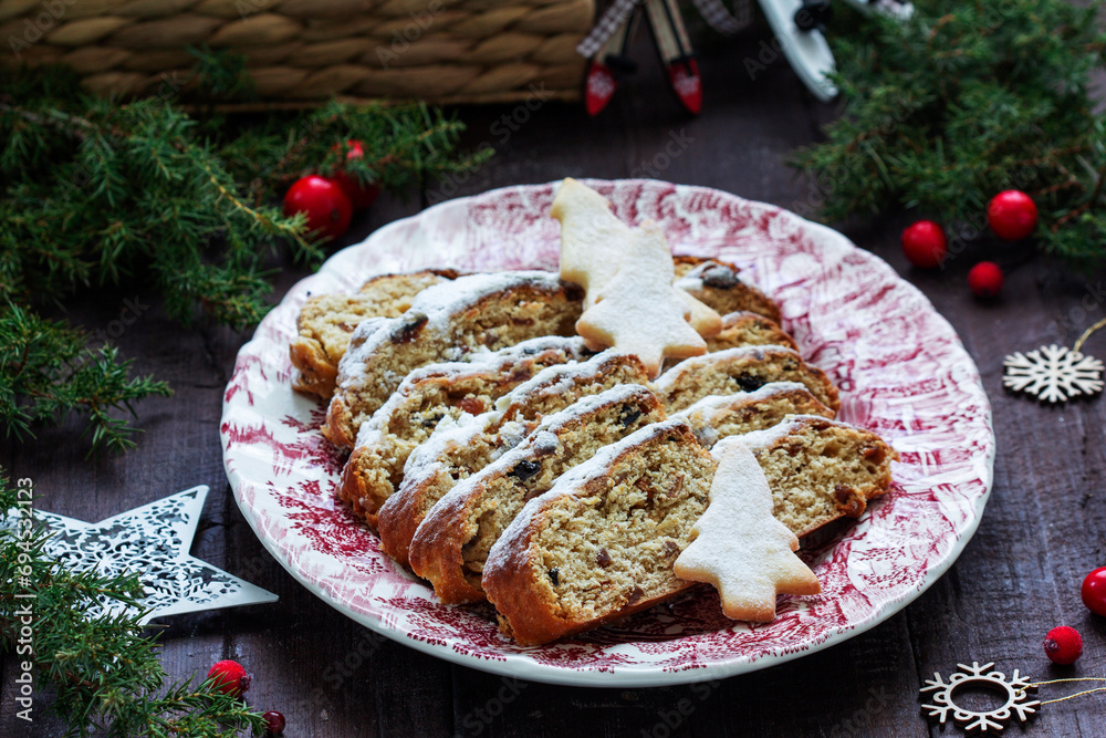 Christmas stollen with dried fruits, nuts and spices, Christmas decorations on a dark wooden background. Rustic style.