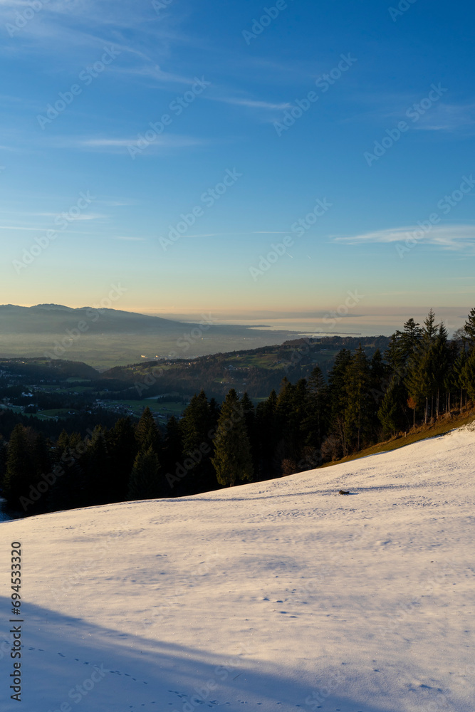 View from snowcovered mountain down onto a lake in evening light View from snowcovered mountain down onto a lake in evening light