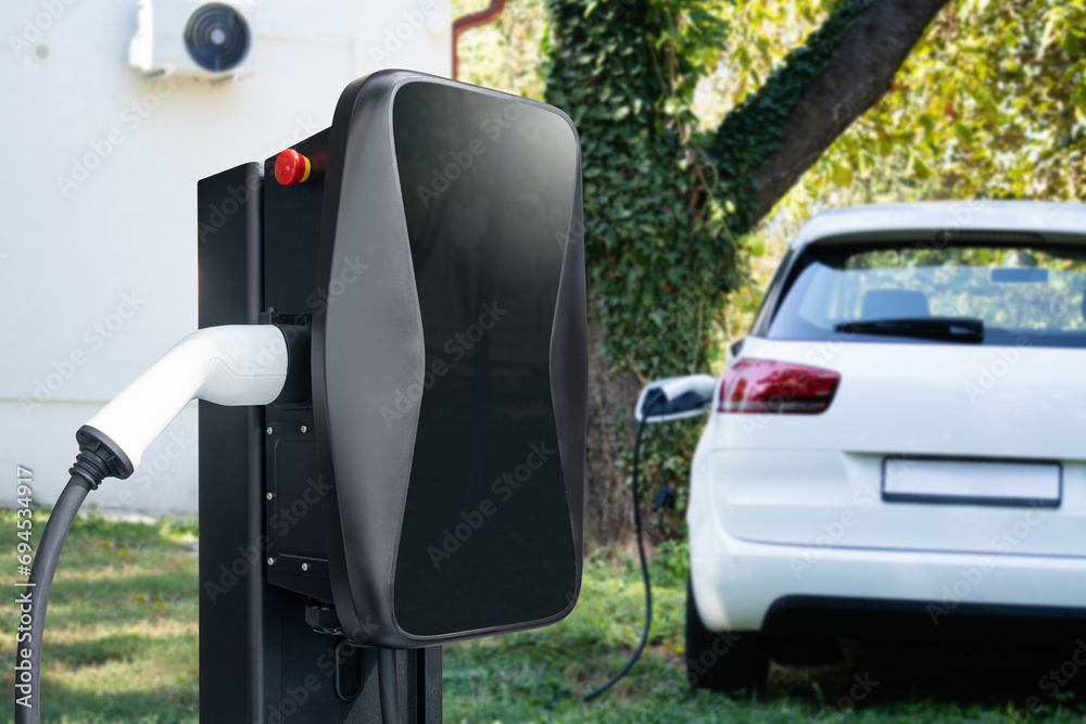 Charging electric car in the yard of a country house Charging electric car in the yard of a country house