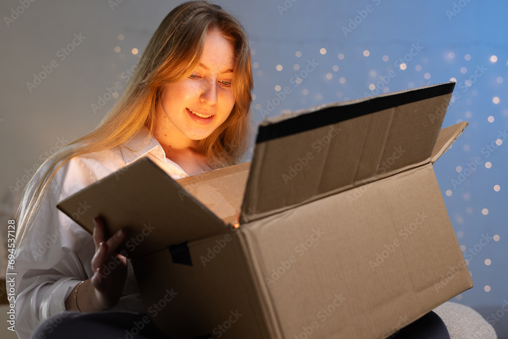 girl unpacks a parcel in the evening, unpacking a mysterious box, online shipping, parcel delivery service girl unpacks a parcel in the evening, unpacking a mysterious box, online shipping, parcel delivery service