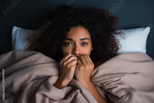 Single woman waiting in bed, looking frustrated and expectant. photo