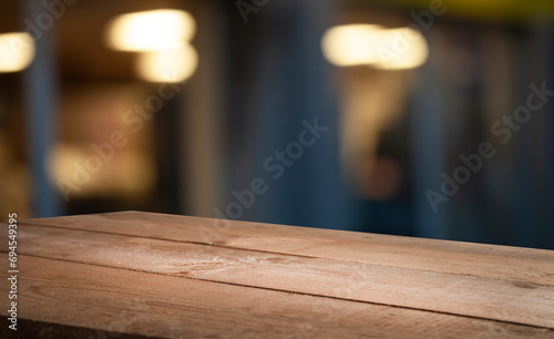 Empty wooden table top on blur light golden bokeh of cafe restaurant, bar in a dark background.