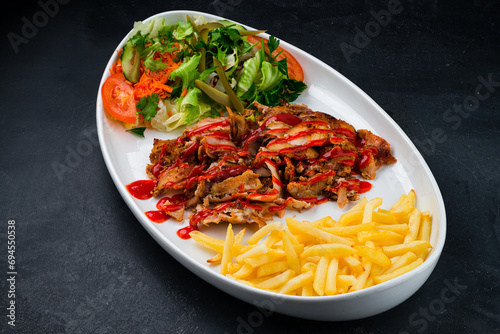 Fried meat with french fries and a salad of pickled cucumbers, tomatoes, carrots, lettuce, parsley and ketchup, shawarma.