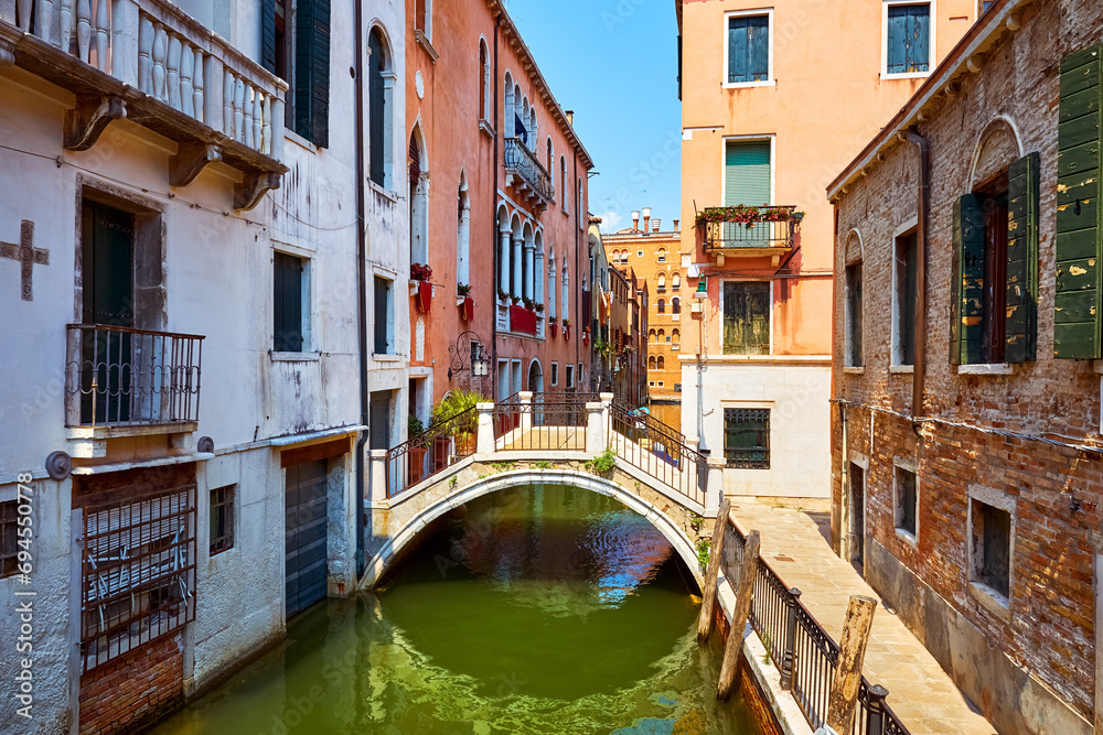 Grand Canal, Venice (Venezia, Italy. Antique bridge over canal among traditional medieval Venetian houses view of old town. Sunny summer day. Famous and popular travel destination. - obrazy, fototapety, plakaty 