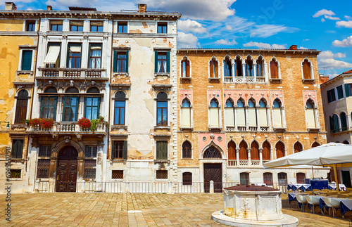 Venice (Venezia, Italy. Antique buildings and traditional italian Venetian architecture on the sunny street view. Day with blue sky clouds. Medieval well at square of venice old town