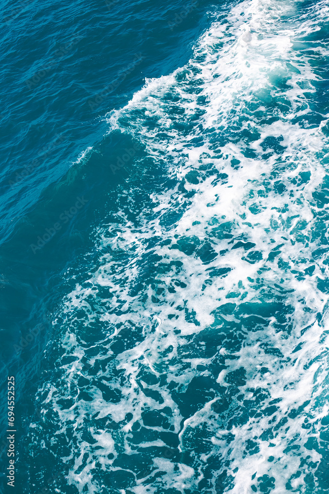 Dark stormy sea with foam, sea water surface, top view. Vertical background.