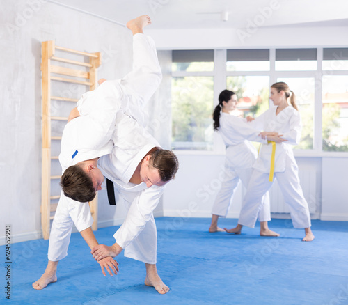 Two men practice grabbing and throwing on sports mats during judo training