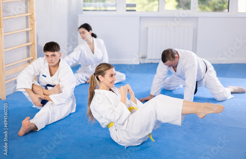 Sports team in kimono doing muscle stretching before karate or judo training
