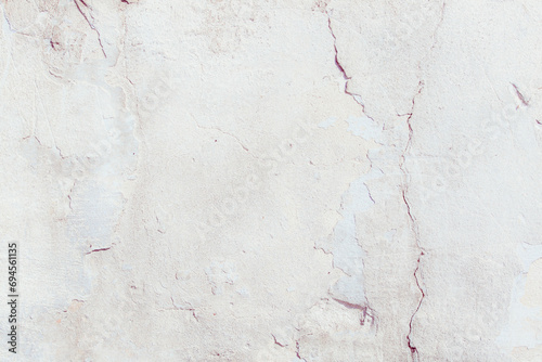 White plaster wall with deep scratches and chips. Various variations of abrasions. Can be used as a background or poster. Fragment of a wall with bumps and peeling paint.