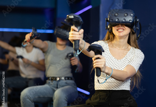 Emotional joyful girl in virtual glasses plays a game by controlling joysticks