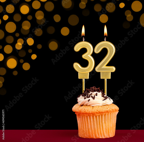 Number 32 birthday candle - Cupcake on black background with out of focus lights photo