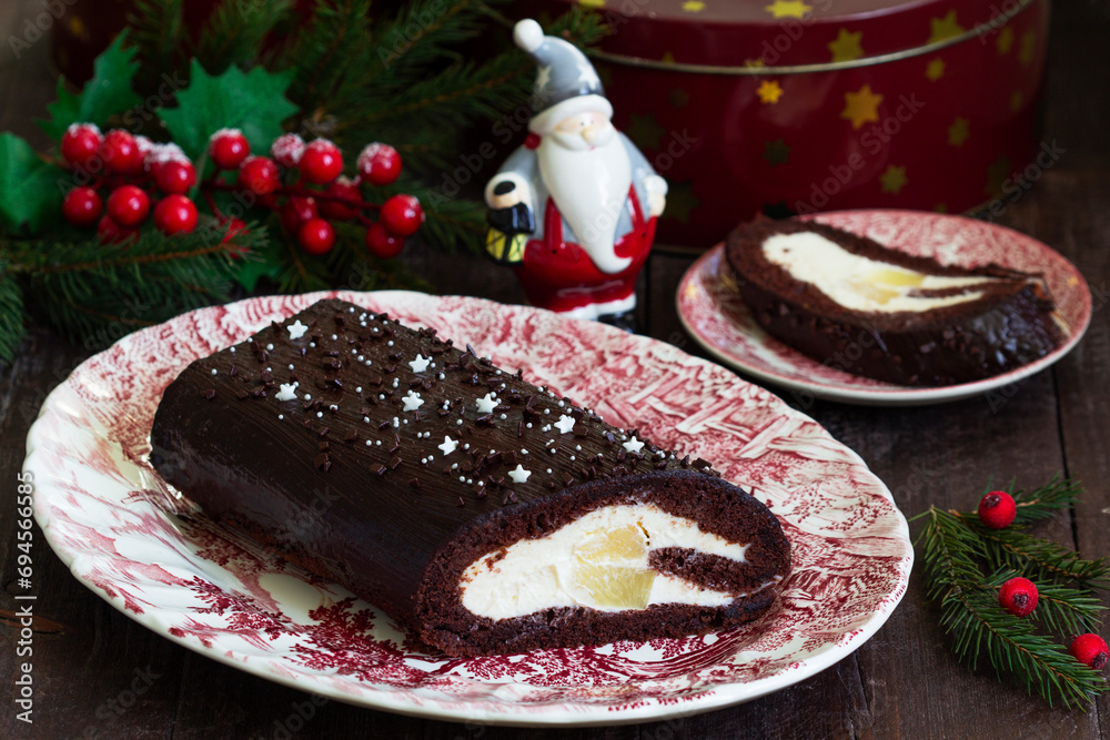 Chocolate roll stuffed with butter cream and pineapple on a Christmas background. Rustic style.
