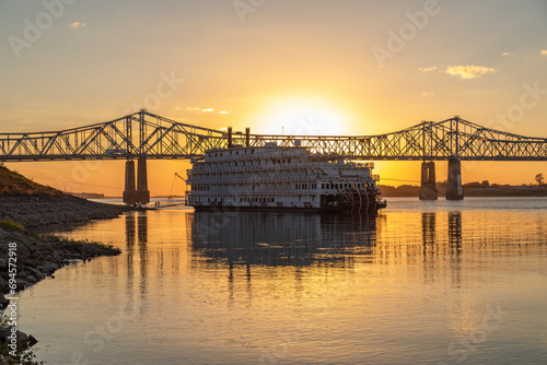 A Paddle Wheeler Cruise Ship at Sunset in Front of the John R Junkin Drive Bridge over the Mississippi River in Natchez, Mississippi  photo